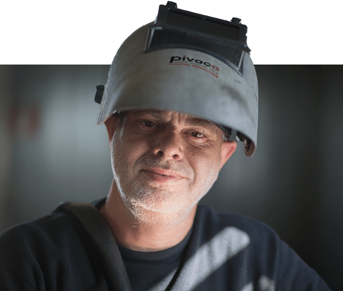 Portret van een man met een lashelm in een werkplaats. Close-up van een industriële werker met veiligheidsuitrusting. Professionele en veilige werkpraktijken in de metaalbewerking of fabricage.